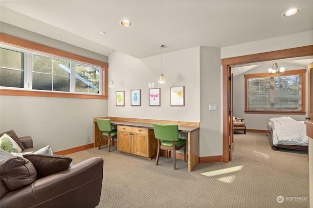 interior space featuring vaulted ceiling, a chandelier, built in desk, and light colored carpet