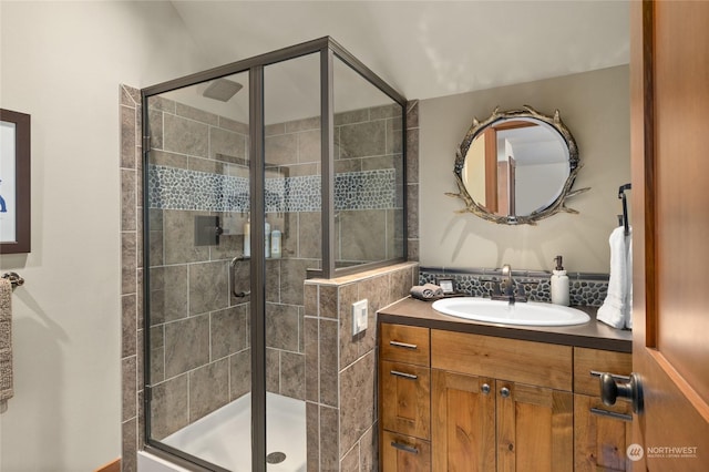 bathroom featuring decorative backsplash, an enclosed shower, and vanity