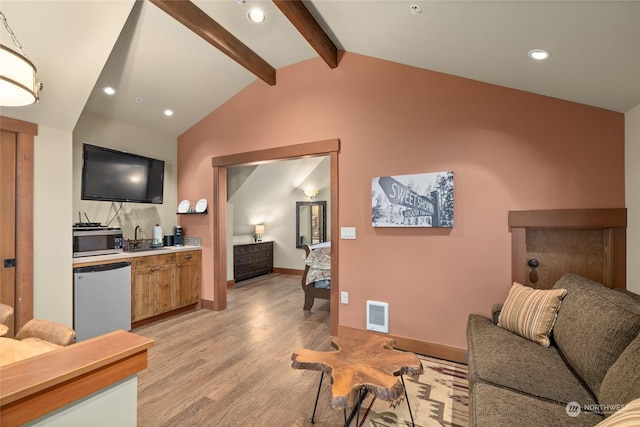 living room featuring indoor wet bar, lofted ceiling with beams, and light wood-type flooring