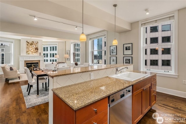 kitchen with pendant lighting, dishwasher, dark hardwood / wood-style flooring, sink, and a center island with sink