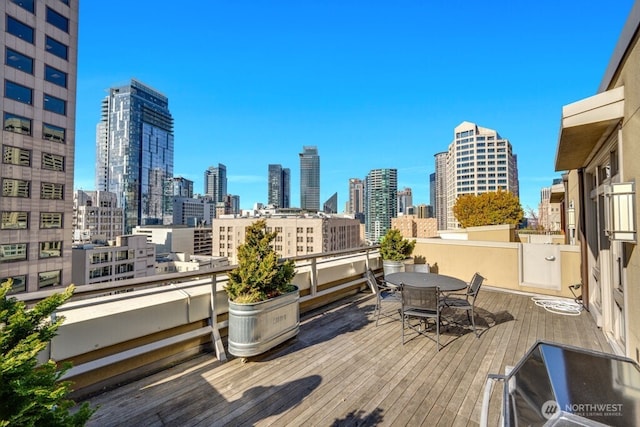 wooden terrace with a view of city and outdoor dining space