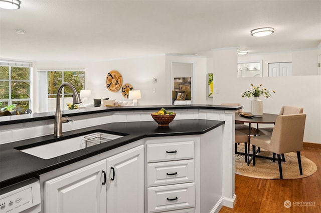 kitchen featuring sink, white cabinets, hardwood / wood-style flooring, and white dishwasher