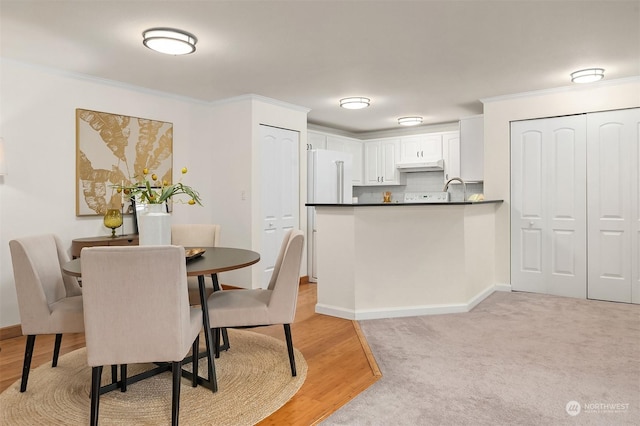 dining space with light hardwood / wood-style flooring and crown molding