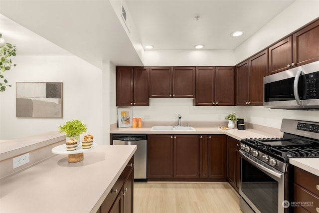 kitchen with dark brown cabinets, appliances with stainless steel finishes, sink, and light hardwood / wood-style floors