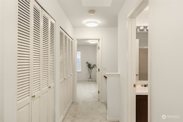 corridor with light carpet and sink