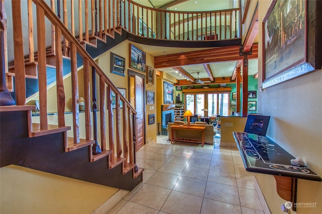 stairway with beam ceiling, tile patterned flooring, and a high ceiling