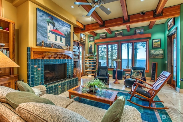 interior space featuring a tile fireplace, light tile patterned floors, ceiling fan, a water view, and beam ceiling