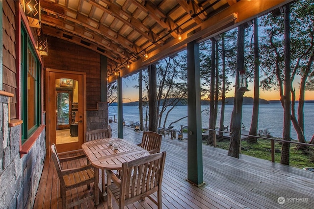deck at dusk featuring a water view