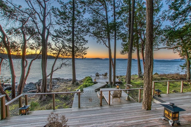 deck at dusk featuring a water view