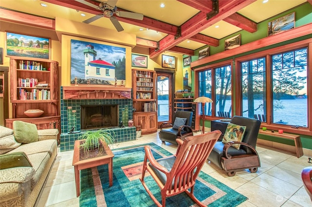 sunroom / solarium with a water view, a fireplace, beam ceiling, and ceiling fan