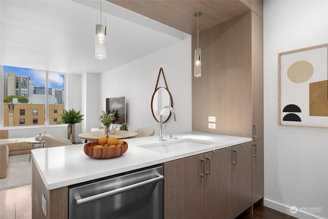 kitchen with sink, stainless steel dishwasher, kitchen peninsula, and dark brown cabinetry