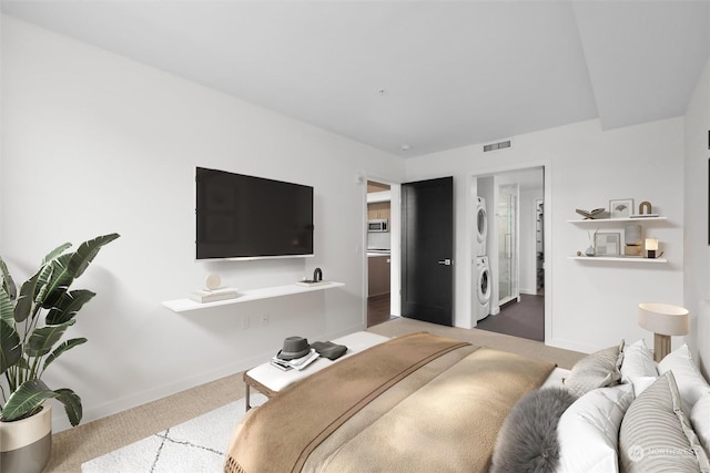 carpeted bedroom featuring stacked washer and dryer