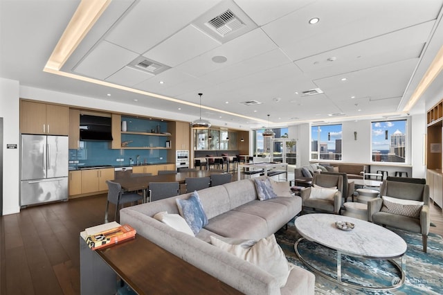 living room with dark wood-type flooring and a raised ceiling