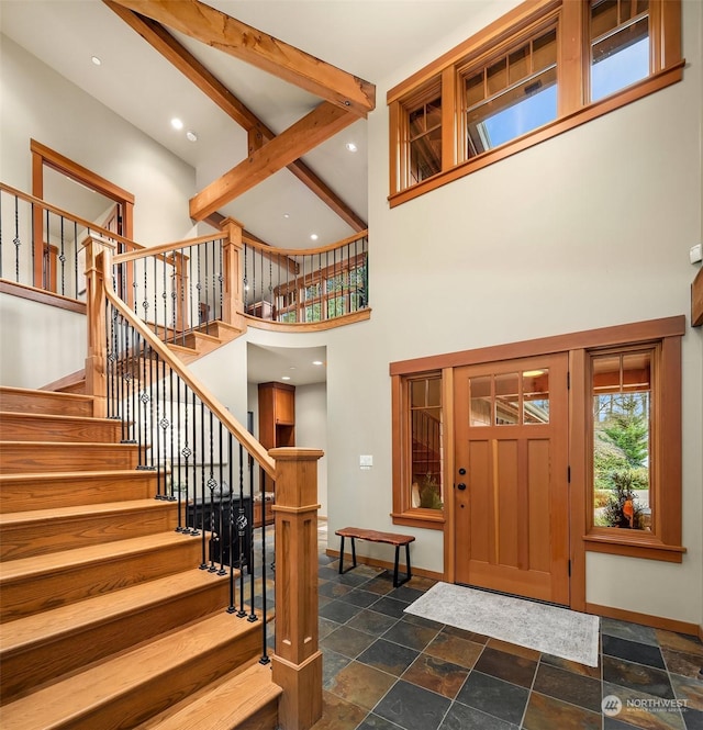 foyer entrance featuring beamed ceiling and a high ceiling