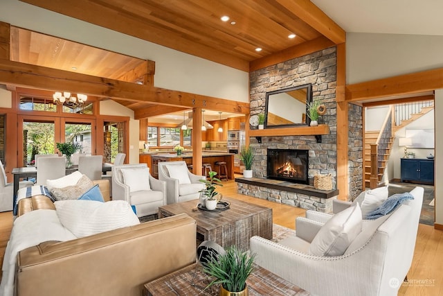 living room with light wood-type flooring, a notable chandelier, a stone fireplace, and beam ceiling