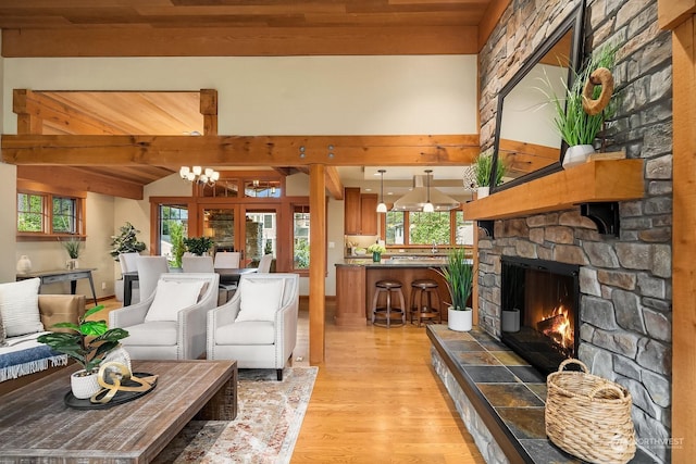 living room with a stone fireplace, wooden ceiling, light hardwood / wood-style flooring, an inviting chandelier, and lofted ceiling with beams