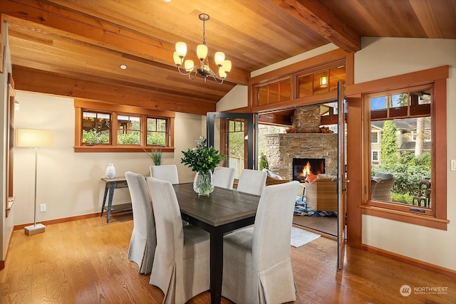 dining room with a fireplace, light wood-type flooring, a chandelier, and a wealth of natural light