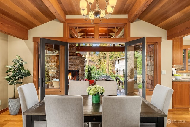 dining room featuring light hardwood / wood-style floors, a fireplace, a wealth of natural light, and an inviting chandelier