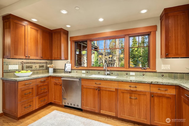 kitchen with stainless steel dishwasher, light hardwood / wood-style flooring, sink, tasteful backsplash, and light stone countertops