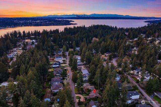 aerial view at dusk featuring a water and mountain view