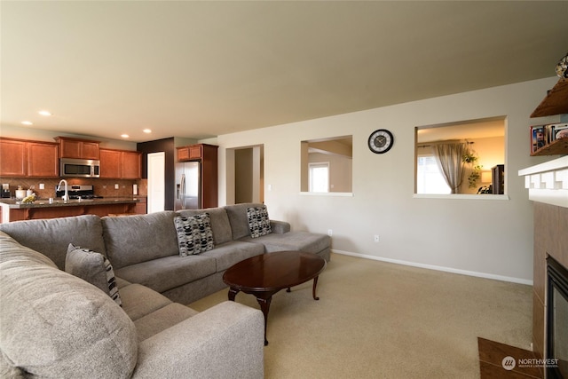 carpeted living room featuring sink and a tiled fireplace