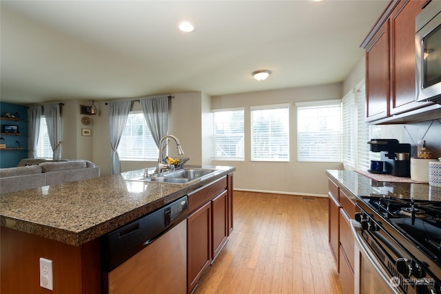 kitchen featuring sink, light wood-type flooring, stainless steel appliances, and a kitchen island with sink