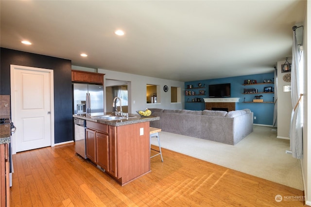 kitchen featuring dishwasher, a kitchen bar, sink, light wood-type flooring, and a center island with sink