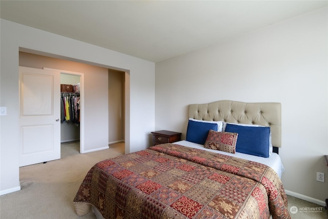 bedroom featuring a walk in closet, light colored carpet, and a closet