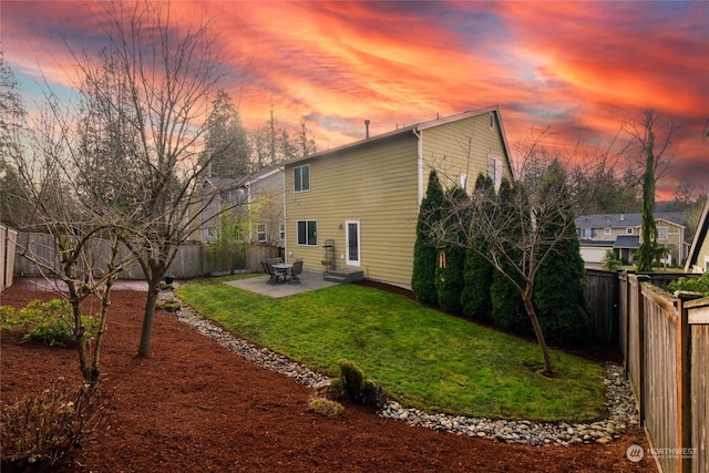 back house at dusk featuring a patio area and a yard