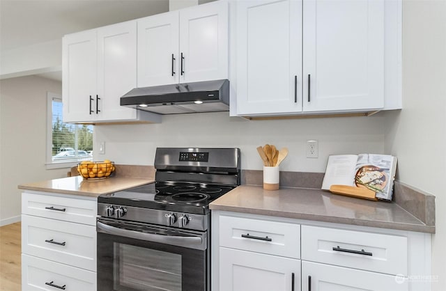 kitchen with white cabinets, electric range, light wood-type flooring, and range hood