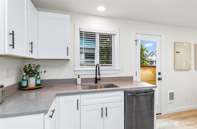 kitchen with sink, stainless steel dishwasher, white cabinets, and light hardwood / wood-style floors