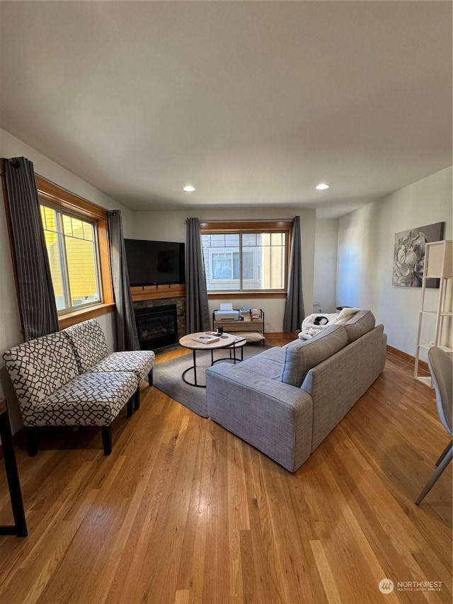 living room featuring a stone fireplace and light hardwood / wood-style flooring