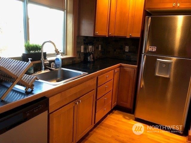 kitchen featuring tasteful backsplash, appliances with stainless steel finishes, sink, and light wood-type flooring