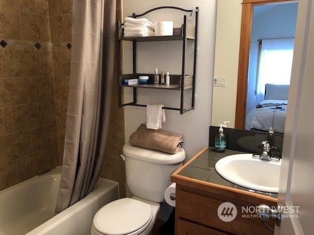 full bathroom featuring vanity, shower / bath combo, and toilet