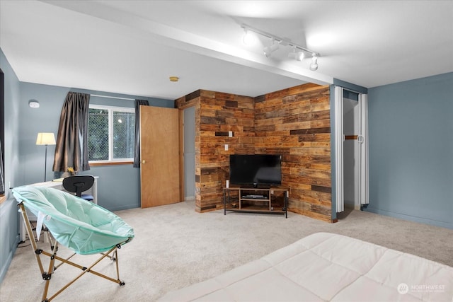 carpeted bedroom featuring track lighting and wooden walls