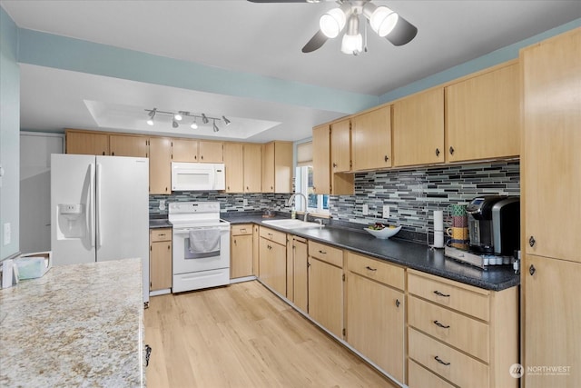 kitchen with sink, white appliances, a tray ceiling, light brown cabinets, and light wood-type flooring