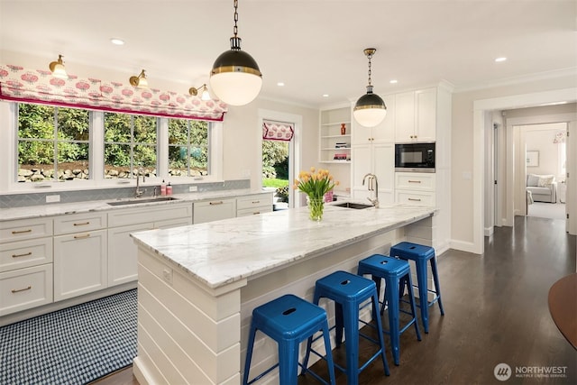 kitchen with white cabinets, ornamental molding, black microwave, and a sink