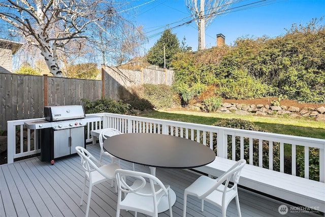 wooden terrace with outdoor dining area, fence, and grilling area