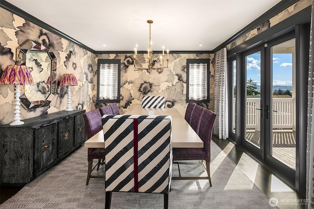 dining area featuring a notable chandelier, french doors, wallpapered walls, and ornamental molding