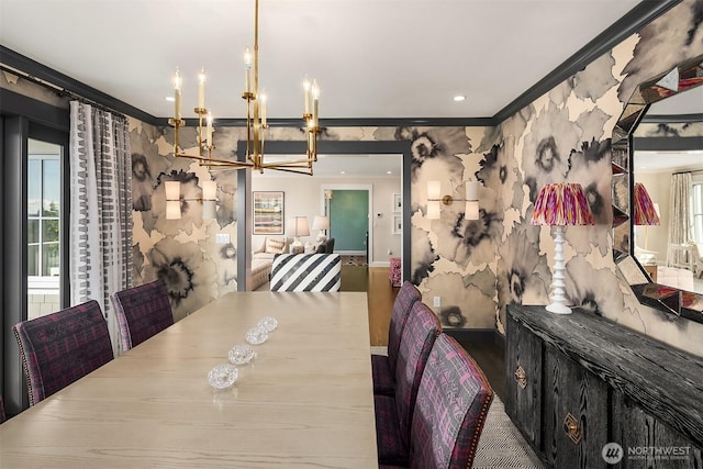 dining space featuring wood finished floors, baseboards, wallpapered walls, ornamental molding, and a chandelier