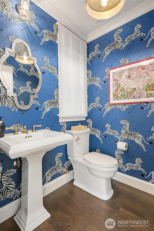 bathroom with baseboards, toilet, wood finished floors, and ornamental molding