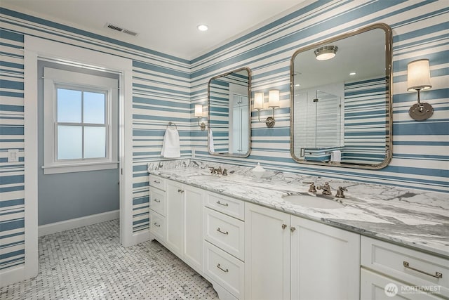 full bath with visible vents, wallpapered walls, baseboards, double vanity, and a sink