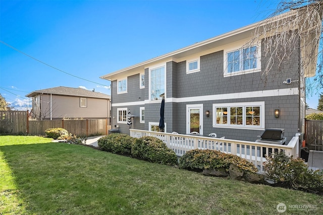 back of property featuring a lawn and fence