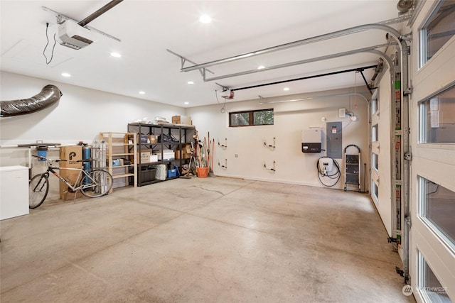 garage with a garage door opener, recessed lighting, and electric panel