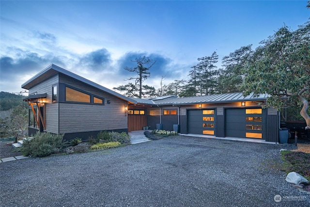 view of front of property featuring driveway, a standing seam roof, a garage, and metal roof