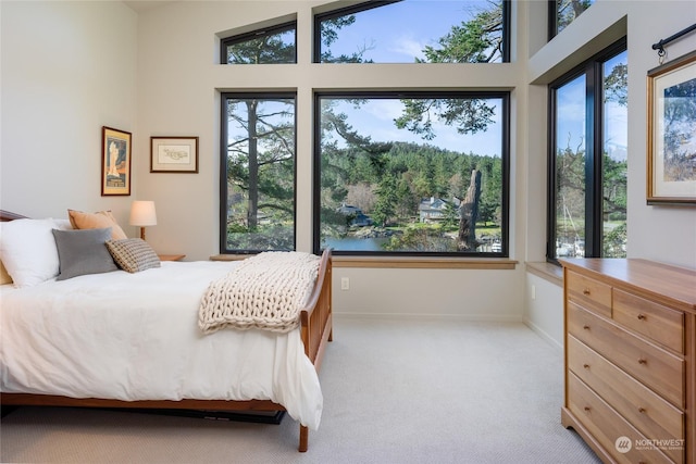 bedroom with baseboards, multiple windows, and light colored carpet