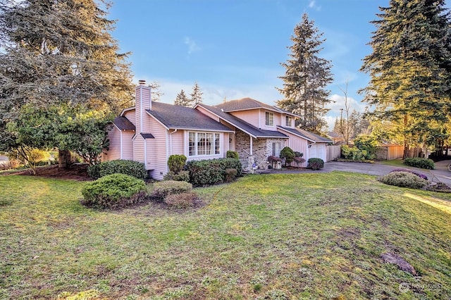 view of front of property featuring a front lawn, fence, aphalt driveway, a chimney, and a garage