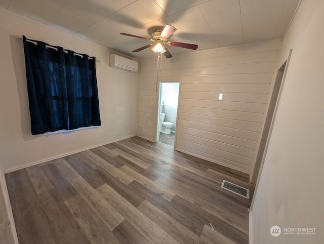 unfurnished room featuring hardwood / wood-style flooring, ceiling fan, a wall mounted air conditioner, and wood walls