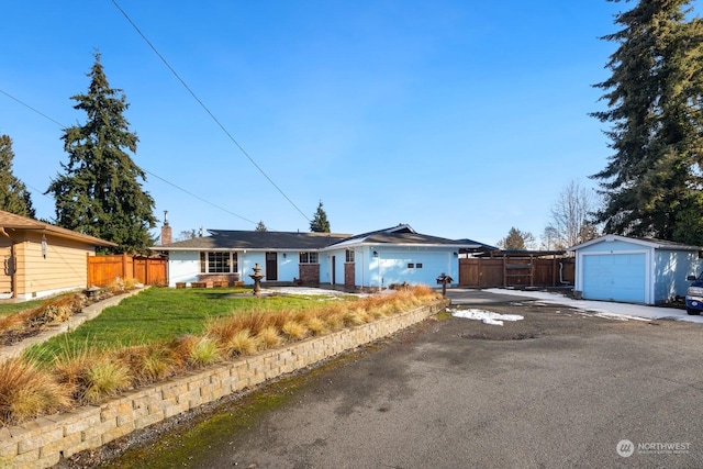 single story home with a garage, an outdoor structure, and a front yard