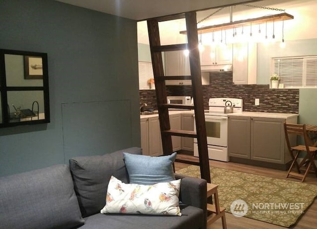 kitchen with pendant lighting, white appliances, decorative backsplash, and light hardwood / wood-style flooring